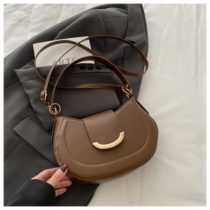 Detail of a dark brown half-moon saddle bag with a polished gold crescent buckle