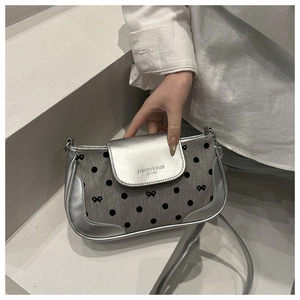 Gros plan d'un sac bandoulière argenté à pois avec détails en cuir et texte embossé