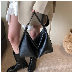 Detail of black large hobo bag featuring natural leather texture and soft synthetic material