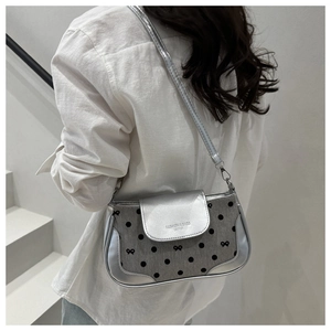 Gros plan du sac bandoulière argenté avec tissu à pois et détails de texture nœud