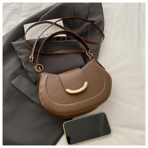 Detail of a dark brown leather shoulder bag with a gold crescent buckle and adjustable strap