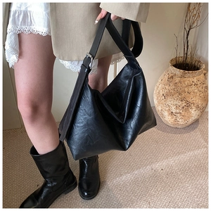 Detail of black faux leather tote bag showing fine grain texture and silver metal buckle
