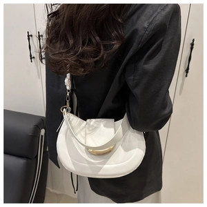 Close-up of white leather half-moon hobo bag with gold crescent buckle on shoulder