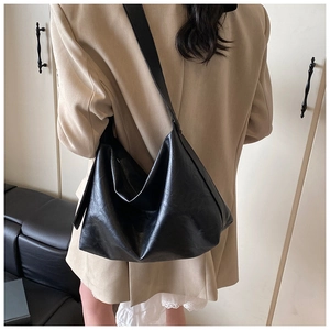 Large black hobo shoulder bag in soft leather texture worn over a beige blazer