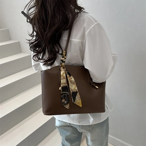 Deep brown minimalist tote bag with vintage silk scarf detail on a model in sunlight