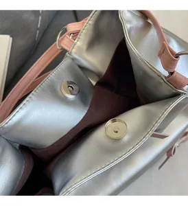 Close-up of silver tote bag interior with dual magnetic buckles and pink strap detail