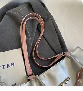 Close-up of silver tote bag featuring pink leather handles and metallic heart studs