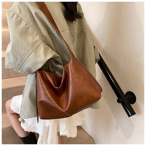 Close-up of brown oversized faux leather tote bag with a soft polished vintage texture