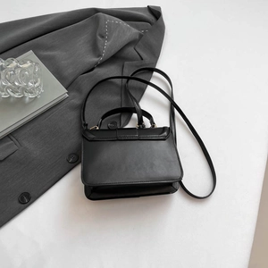 Minimalist black rectangle flap shoulder bag with matte leather finish on a white surface