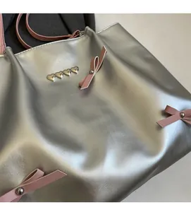 Detail of silver tote bag featuring pink ribbons and heart-shaped metal studs