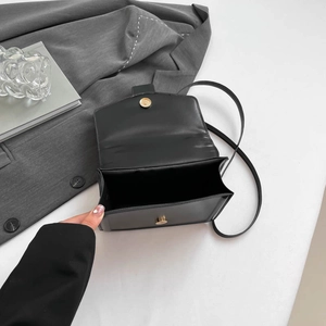 Minimalist black leather crossbody bag with gold hardware shown with its interior compartment
