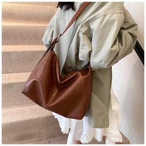 Close-up of caramel brown soft leather tote bag with elegant draped folds on a strap
