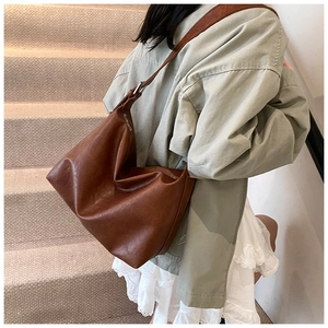 Brown leather hobo bag side detail with metal zipper and soft texture over the shoulder
