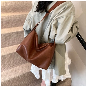 Side view of a large brown slouchy tote bag with soft leather texture on a shoulder strap