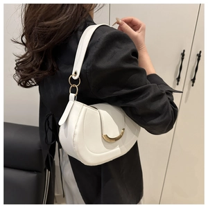 Detail of white half-moon shoulder bag with golden U-shaped hardware on leather