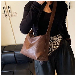 Close-up of vintage brown tote bag with wide shoulder strap and distressed leather texture