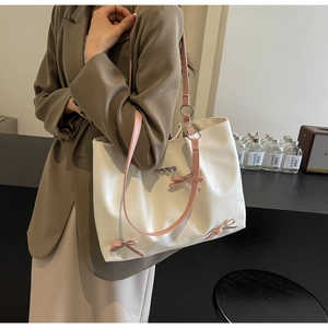 Detail view of stylish bow decoration and heart charm on the cream pink tote bag