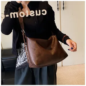 Detail view of large brown retro tote bag with adjustable wide shoulder strap on model
