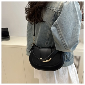 Detail of a black half-moon saddle bag with golden metal hardware on a female model