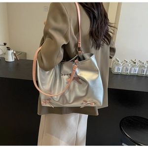 Detail of silver tote bag featuring pink ribbons and metal heart charms on shoulder