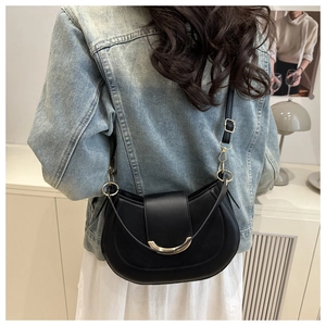 Close-up of black crescent saddle bag featuring gold metal trim and adjustable strap