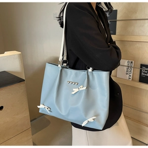 Haze blue PU leather tote bag with white bow and heart rivets on model for daily commute