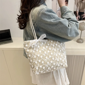 Beige woven straw tote bag with white daisy embroidery and lace bow decoration