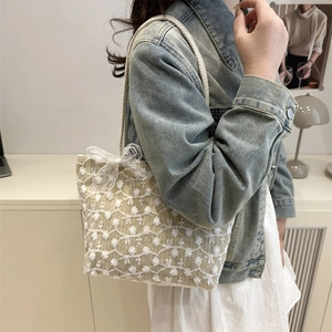 Beige lace woven tote bag with floral embroidery and bow detail shown on a model