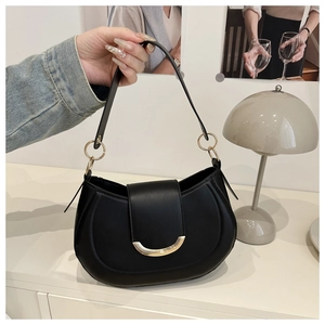 Detail of minimalist black semi-circular handbag with smooth matte leather and gold hardware
