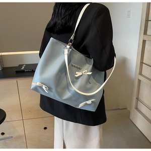 Detail of blue nylon tote bag with white bows and silver heart studs in lifestyle setting