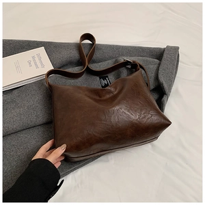 Detail of soft dark brown leather tote bag showing textured surface and wide strap