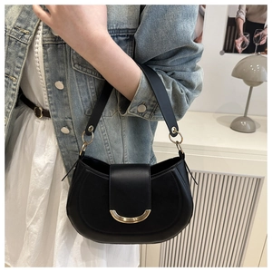 Detail of a black crescent leather bag with gold crescent buckle and metal ring