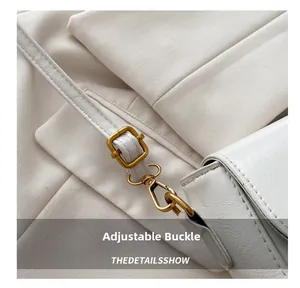 Detail of adjustable golden metal buckle and white leather strap of a vintage bag