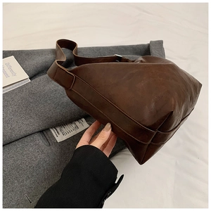Close-up of a dark brown vintage faux leather tote bag with retro textures and soft strap