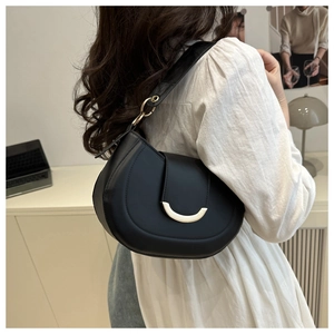 Detail of minimalist black saddle bag with golden half-moon buckle and premium leather finish