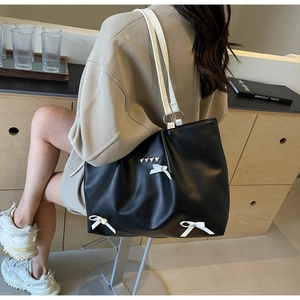 Close-up of black large tote bag with white bows and heart-shaped metal studs details