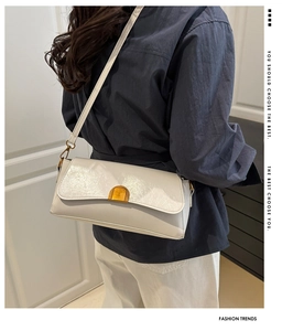 Détail du sac baguette en cuir verni blanc avec un fermoir métallique doré de luxe