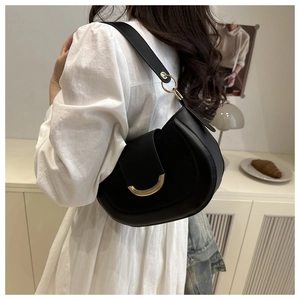 Close-up of black leather saddle bag featuring a stylish golden crescent metal buckle
