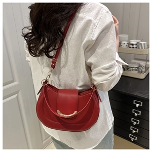 Rear view of a model wearing the red leather saddle bag with gold U-shaped metal hardware