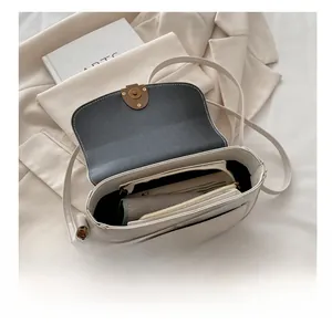 Interior view showing spacious compartments of a cream-white saddle crossbody bag