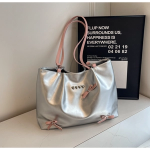 Silver metallic tote bag detail with pink bows and heart-shaped metal studs