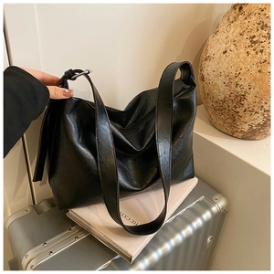 Detail of minimalist black large tote bag with pleated texture on a silver suitcase
