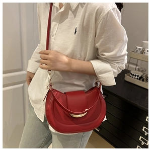 Red crescent shoulder bag with gold metal buckle shown on a model in casual outfit