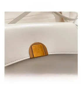 Détail macro de la boucle dorée sur sac bandoulière crème avec coutures soignées