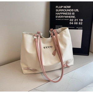 Detail of cream tote bag featuring pink bows and silver heart charm decoration