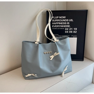 Detail of light blue tote bag with white bows and heart rivets on marble stairs