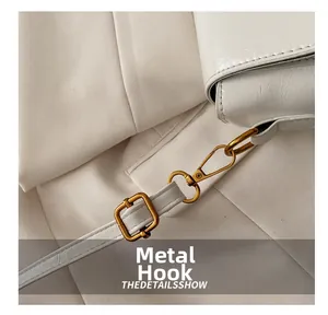 Detail of elegant gold metal hook and hardware on a textured white faux leather bag