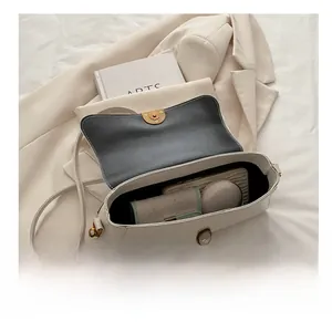 Vue de dessus de l'intérieur de ce sac bandoulière en cuir crème avec des objets du quotidien