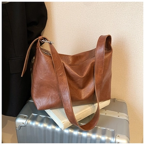Detail of vintage brown PU leather tote bag with soft texture and silver buckle accents