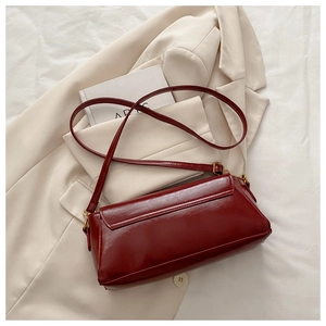 Detailed close-up of dark red leather shoulder bag with vintage gold metal hardware